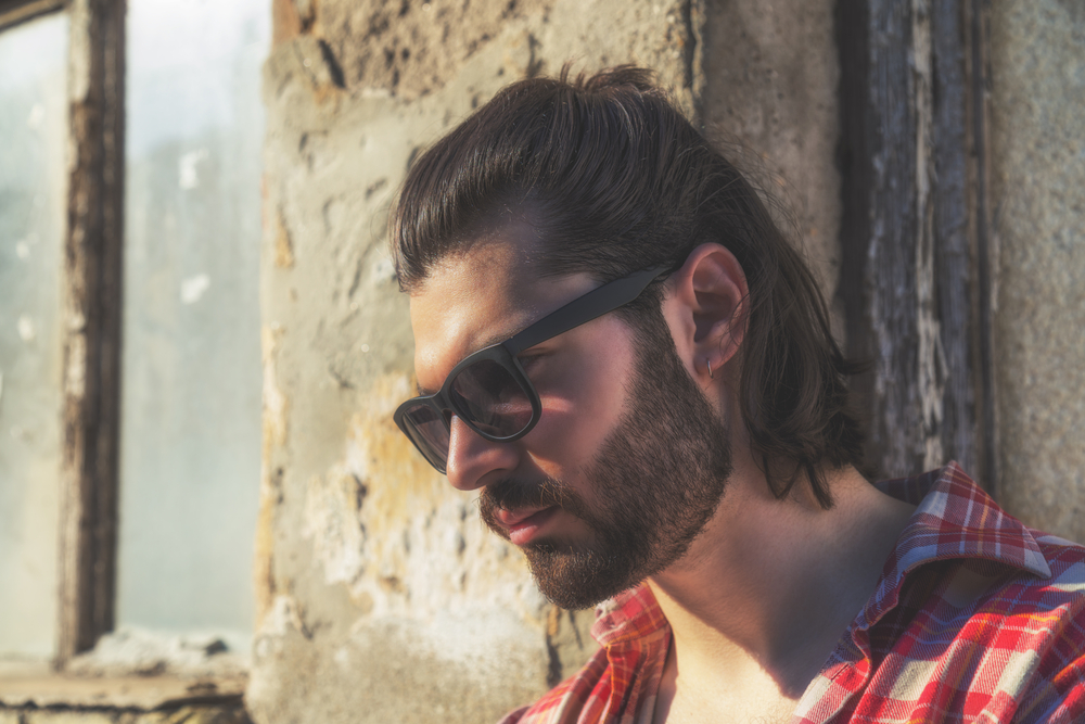 A guy with thick hair and an oval face shape wearing a short Mexican mullet haircut creates an edgy appearance for his straight hair.