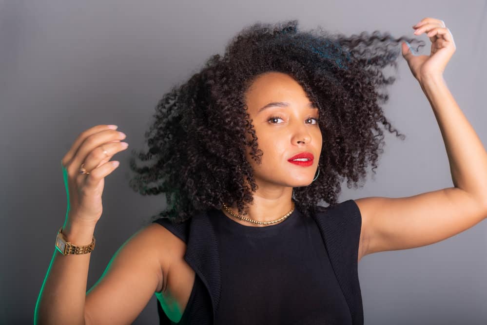 As she's air drying curly hair, she gently squeezes out excess water from her wet curls, allowing her natural curl pattern to form and shine through.