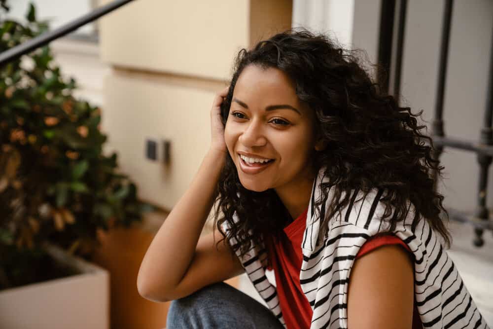 Her wet curly hair is protected during sleep with a satin bonnet and loose bun, maintaining curl definition and preventing frizz during her curly hair night routine.