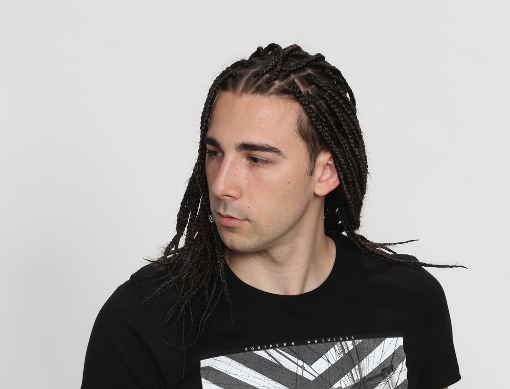 The white man's box braid hairstyle, skillfully executed with small sections of hair, forms a striking zigzag part that adds a unique twist to his look.