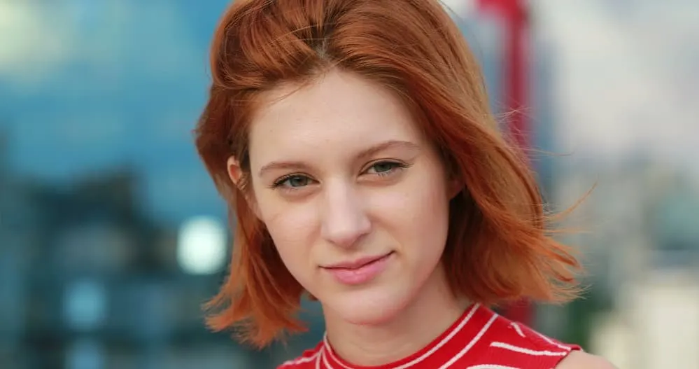 Short Hairstyles for Teens: Hairstyle Ideas for Teenage Girls 1 A super stylish young woman with red straight hair wearing a short hairstyle with blunt bangs styled with an organic holding spray on her oval face shape.