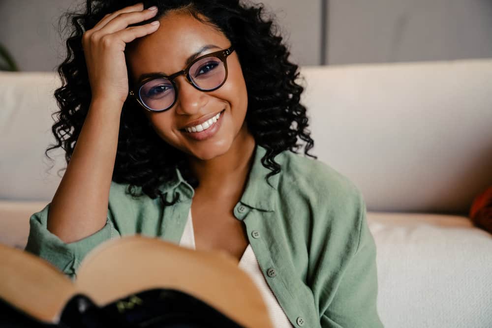 A young African American female with greasy roots due to excess oil sitting on her fine hair strands used a foam dry shampoo to absorb oil and clean hair.