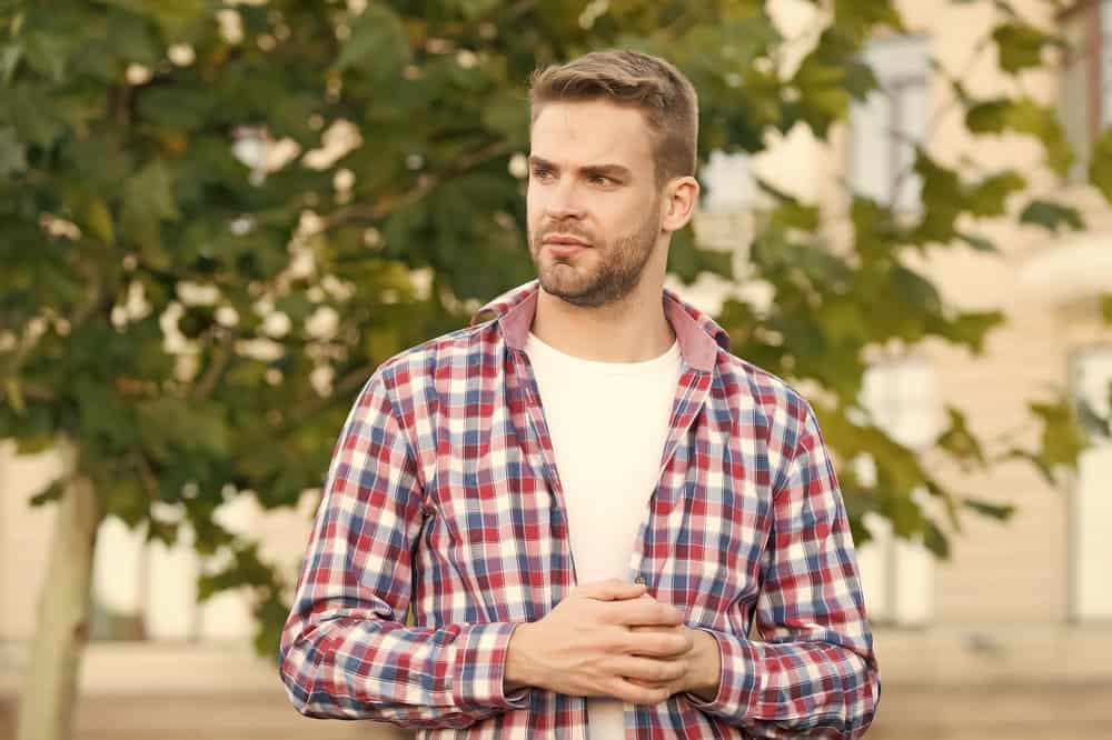 His clean-shaven face complements his big forehead haircut, creating a harmonious balance and emphasizing his facial features.