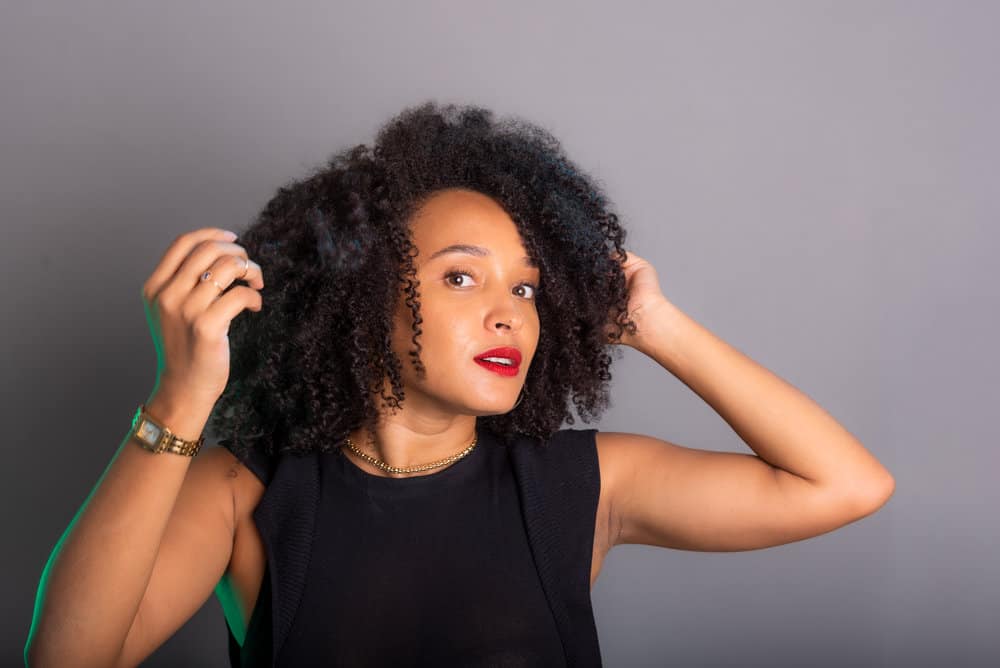 With her wet hair, she applies a leave-in conditioner and natural oils to highlight her natural texture and bring out the beauty of her curly, fine hair.