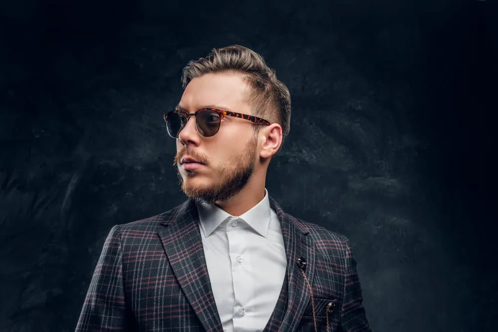Peaky Blinders Haircut: How to Do Peaky Blinders Haircuts 3 Embracing the iconic Peaky Blinders style, the gentleman sports an Arthur Shelby haircut and a full, well-groomed lumberjack beard.