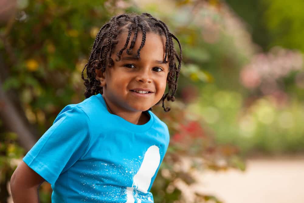 A cute African American toddler wearing little boy braids on his type 4 natural hair strands, a braided hairstyle that was created with zig-zag pattern.