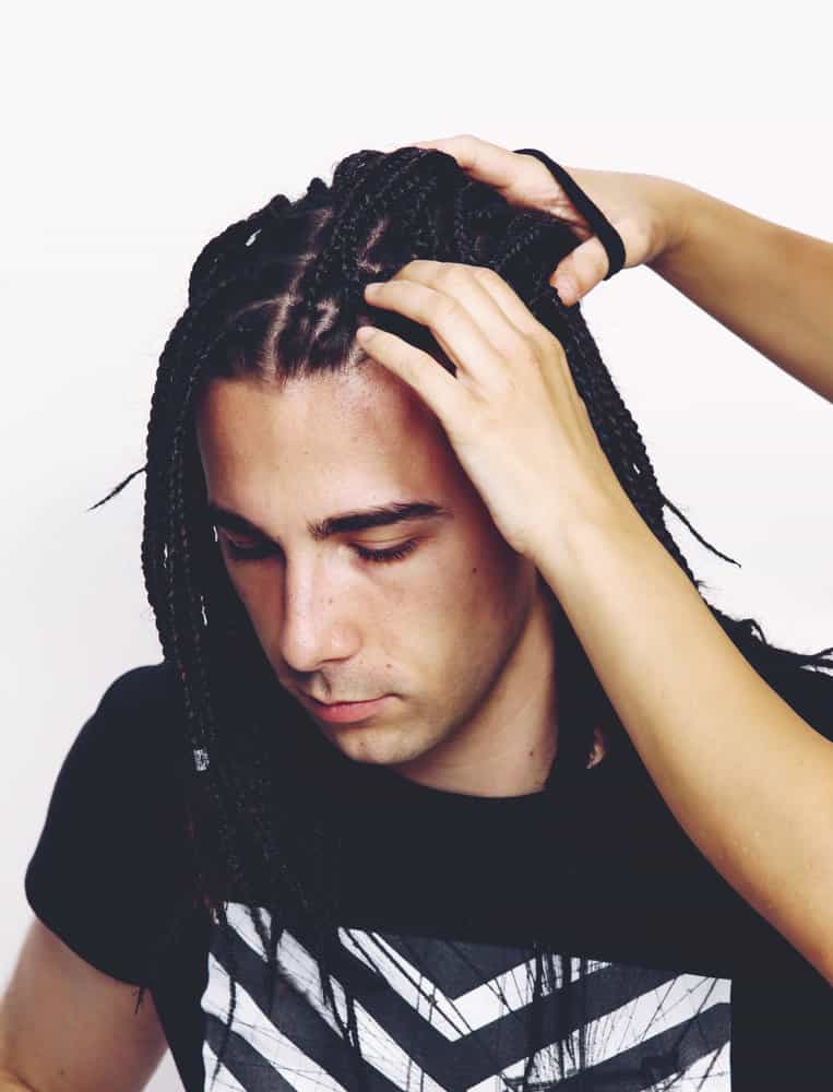 The woven man braids on the white guy's head draw attention to his unique sense of style, blurring the boundaries between cultural aesthetics.