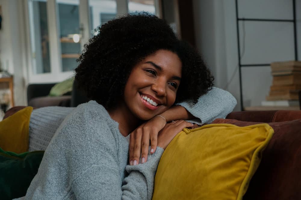 The pretty black woman showcases her voluminous curly hair with a stunning Deva cut, perfectly tailored to her 4A natural curl pattern.