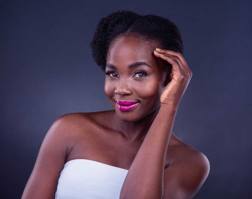 A gorgeous black girl with type 4 natural hair showcases the importance of sealing moisture in the hair shaft with light sealing oils, like olive or peppermint oil.