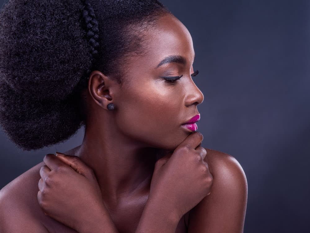 A black girl showcases moisturized hair that was styled with light oil so every hair strand feels soft and healthy. 