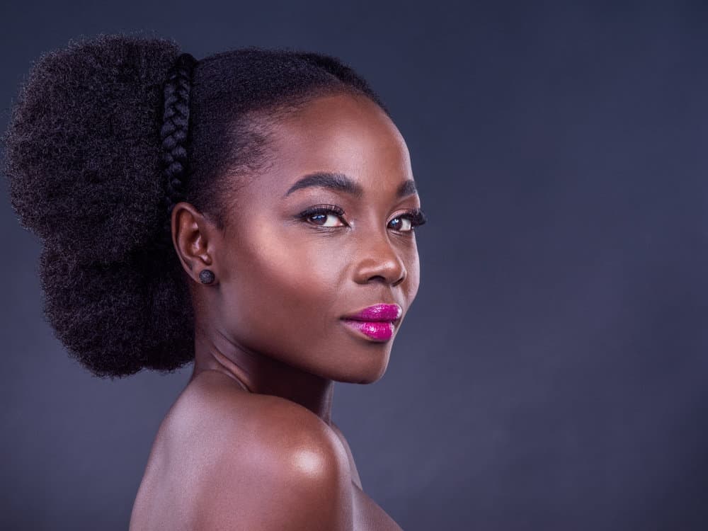 The beautiful black girl retains moisture in her hair strands with a moisturizing routine featuring a natural oil like jojoba oil to her natural hair moisturized.