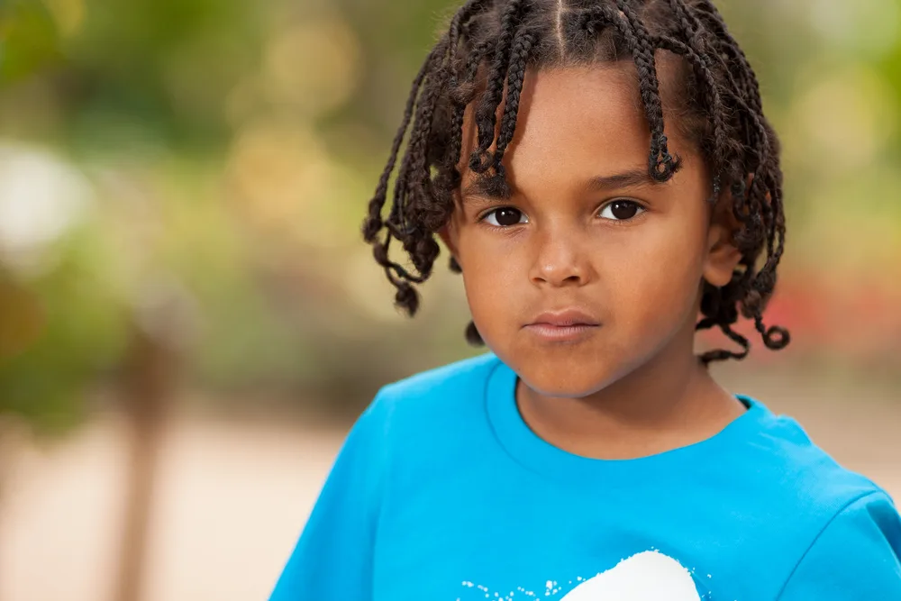 Toddler and Little Boy Braids: 15 Cute Braided Hairstyles 4 The cute African American toddler rocks long, tiny braids on his type 4 natural hair, showcasing a stylish and age-appropriate braided hairstyle.