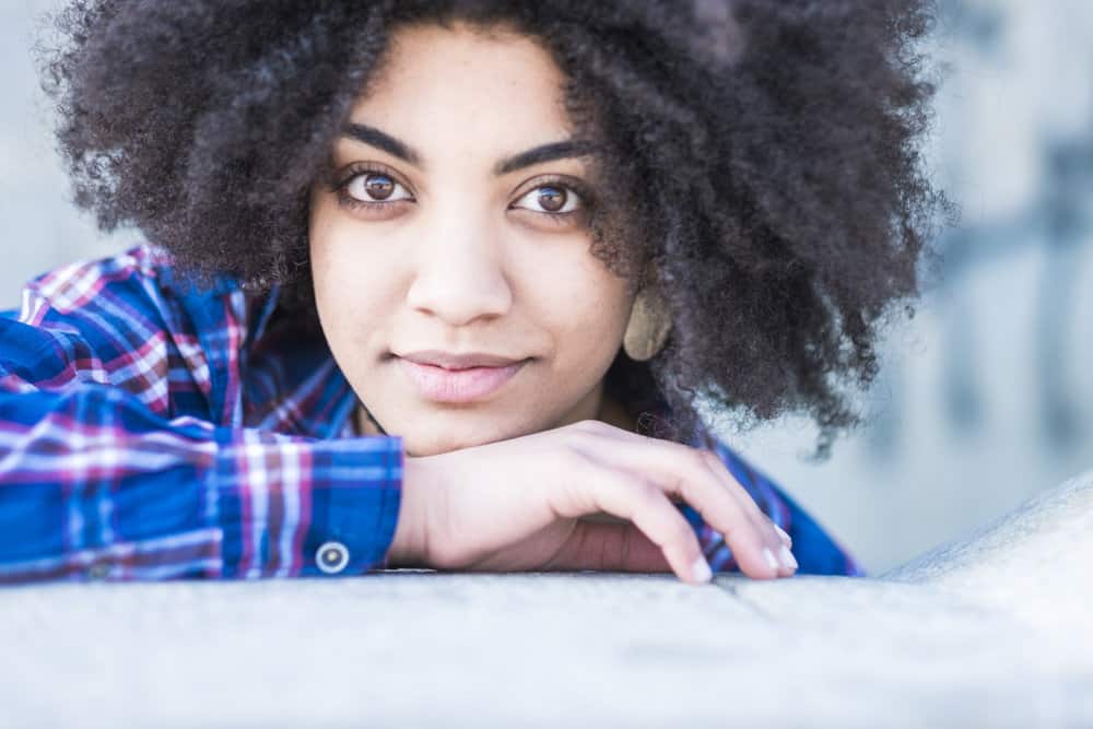 With her natural curls, she gently brushes her dry hair using a Tangle Teezer, effectively detangling her tangled hair strands and enhancing her tight curls.