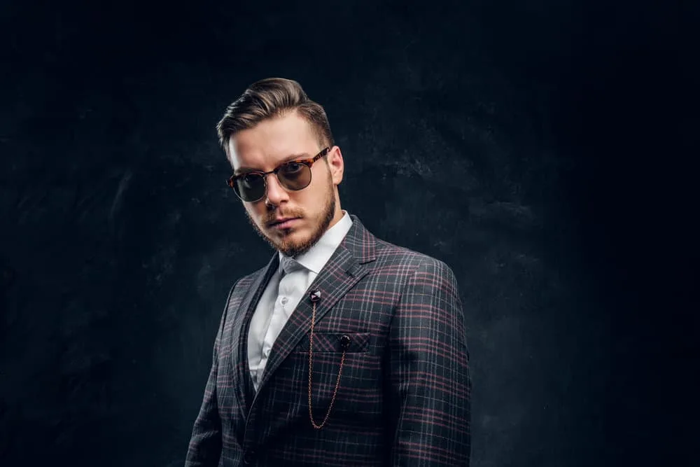 Peaky Blinders Haircut: How to Do Peaky Blinders Haircuts 1 A young white man wearing a John Shelby haircut with a disconnected undercut from Peaky Blinders and a lumberjack-style beard.