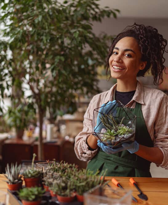 A young African American woman with an aloe vera plant that she'll use to promote hair growth and smooth an irritated scalp.