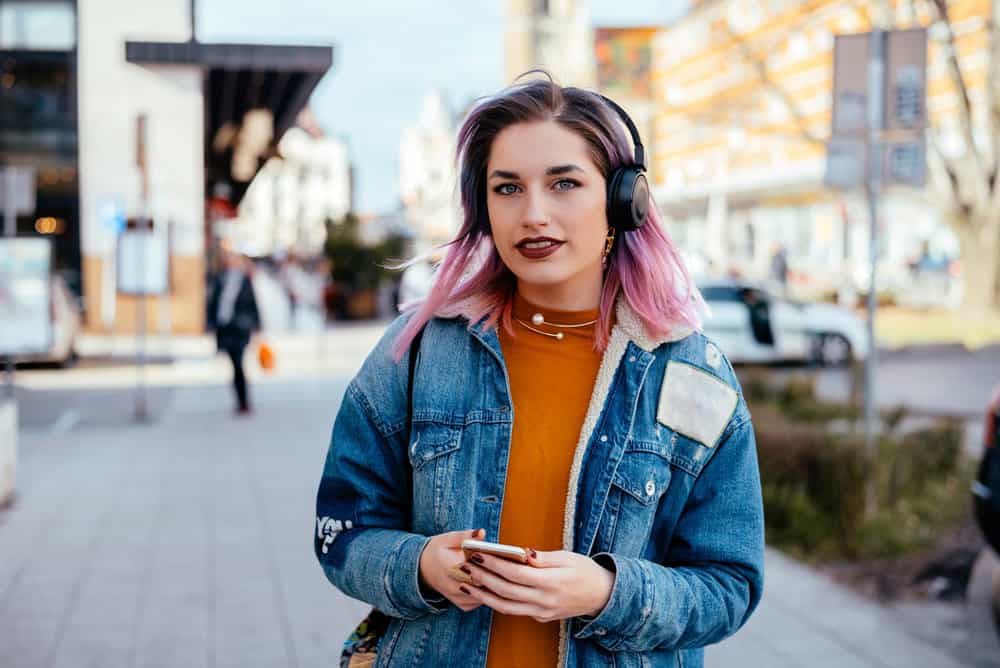 The purple dyed hair saturates her dark blonde hair, creating a vibrant and eye-catching pink and blue tone.