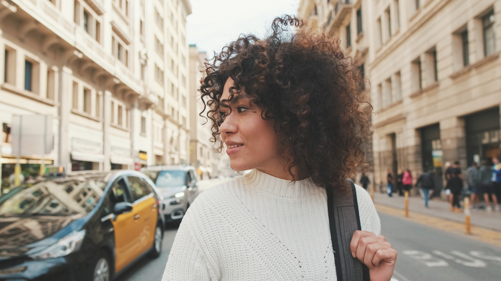 A young female woman with natural curls plans to follow a hair care regimen based on the curly girl method after using a gentle clarifying shampoo to clean her hair.