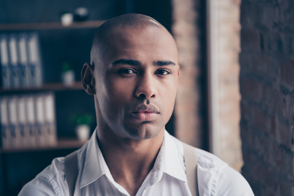 A confident black guy with sensitive skin and razor bumps used a top-rated professional hair clipper with quality blades and blade oil to avoid skin irritation.