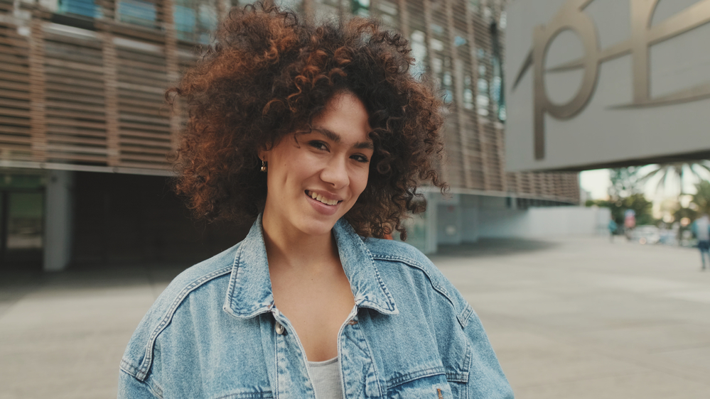 A cute young black girl wearing her natural curly pattern on type 3 natural hair that's styled with a combination of shea butter with rice amino acids and natural oils.