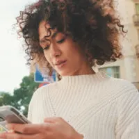 A beautiful, light-skinned black girl wearing frizz-free curls on type 3 wavy hair that was styled using curl cream and shea butter while following the Curly Girl Method.