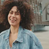 A black lady wearing defined curls that highlights her natural texture and fine hair after using a Dyson Supersonic hair dryer instead of air drying her bouncy curls.