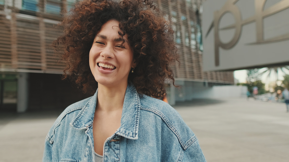 A black lady wearing defined curls that highlights her natural texture and fine hair after using a Dyson Supersonic hair dryer instead of air drying her bouncy curls.