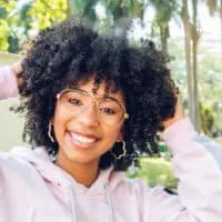 A cute black girl with light-brown skin and naturally curly hair wearing her type 3 natural hair texture in a style with effortless black curly waves and defined tight curls.