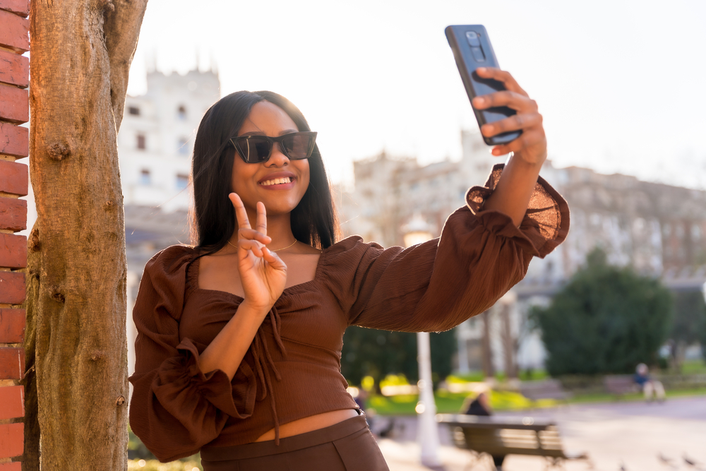 A beautiful young African woman that takes a selfie wants to bleach wet hair strands a light brown hair color and then style it with natural oils to avoid hair damage.