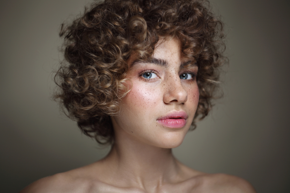 Rocking curly hair bangs with her tight curly hair, this girl's hairstyle adds a chic and edgy vibe to her overall curly fringe.