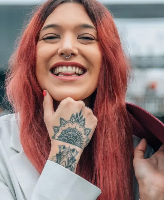 A beautiful female wearing a popular e-girl hair trend with black and red colored hair with a middle part and winged eyeliner.
