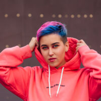 A cute young girl with colorful short hair is wearing a gender neutral haircut that looks like an androgynous look that Miley Cyrus would wear.