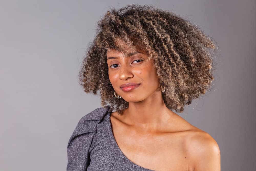 A cute black girl with oily hair used an organic shampoo and conditioner treatment before styling her natural hair strands with a natural bristle brush.