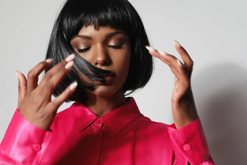 How to Cut a Bob: Cutting a DIY Bob Hairstyle on Yourself 1 A cute African American female with thick hair wearing a layered bob haircut that has subtle layers that perfectly fit her oval face shape.