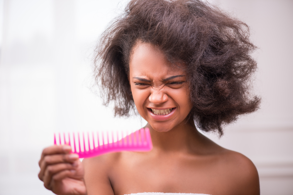 The matted hair extensions in her afro-textured hair require extra care and patience to untangle without causing damage.