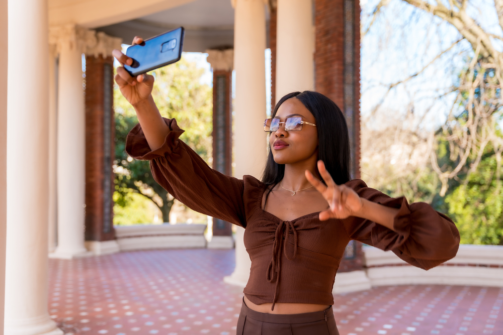 An African American female with her hair bleached taking a selfie of real human hair after using organic hair treatments to reduce hair breakage.