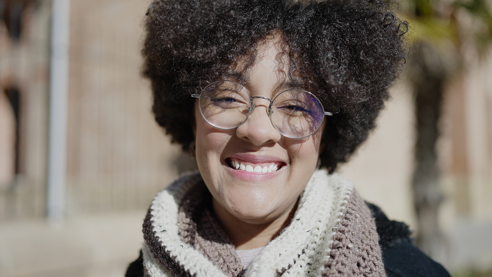 A young black female with a looser hair texture wearing a curly hairdo that was styled with whipped shea butter, coconut hair, and organic gel hair products.