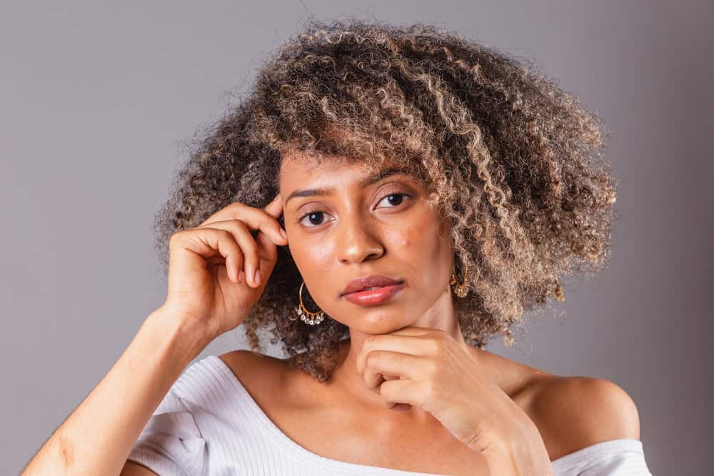 A black girl with thick hair was cleaned with a soap nut liquid natural shampoo and styled with essential oils, like a lavender essential oil.