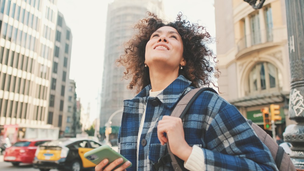 With her mobile phone in hand, this beautiful black woman is wearing hair extensions enhancing the volume of her own hair with micro-links hair extensions.