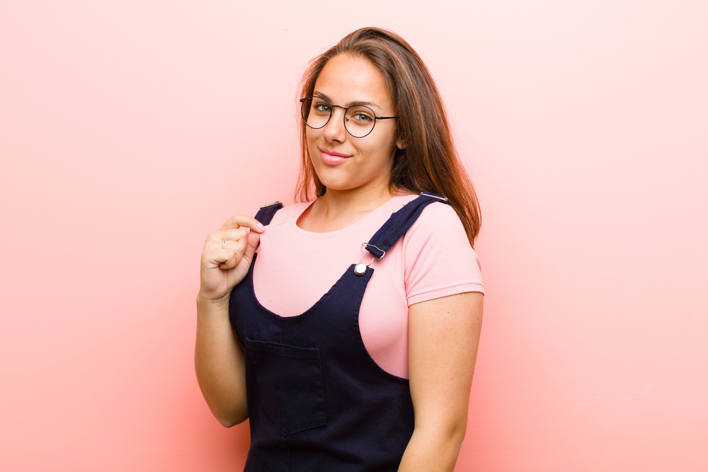 A beautiful white girl with waist-length curly hair enhanced with straight hair extensions before being styled with a curling iron and loose ends.