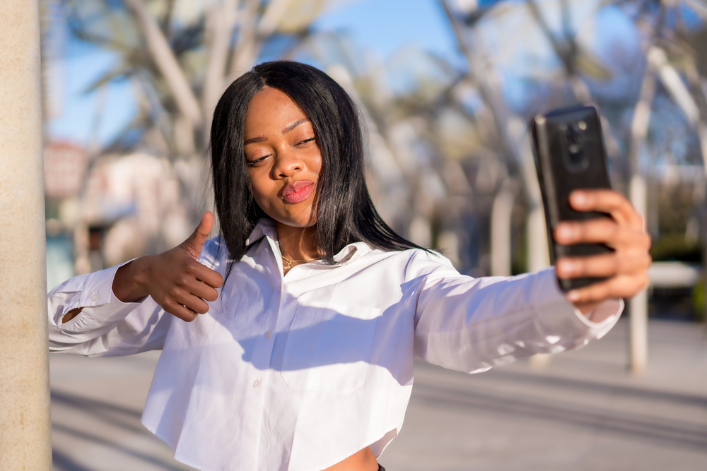 A young African American woman wearing a synthetic hair wig made with body wave hairpieces and hair extensions.