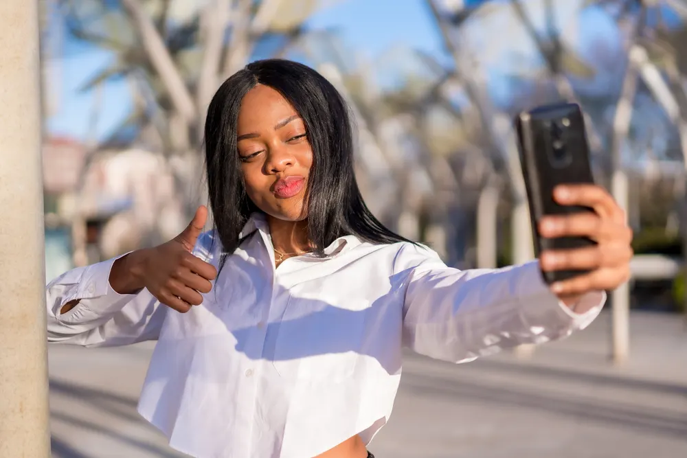 Where to Get a Wig: Where to Buy a Wig Locally or Online 1 A young African American woman wearing a synthetic hair wig made with body wave hairpieces and hair extensions.