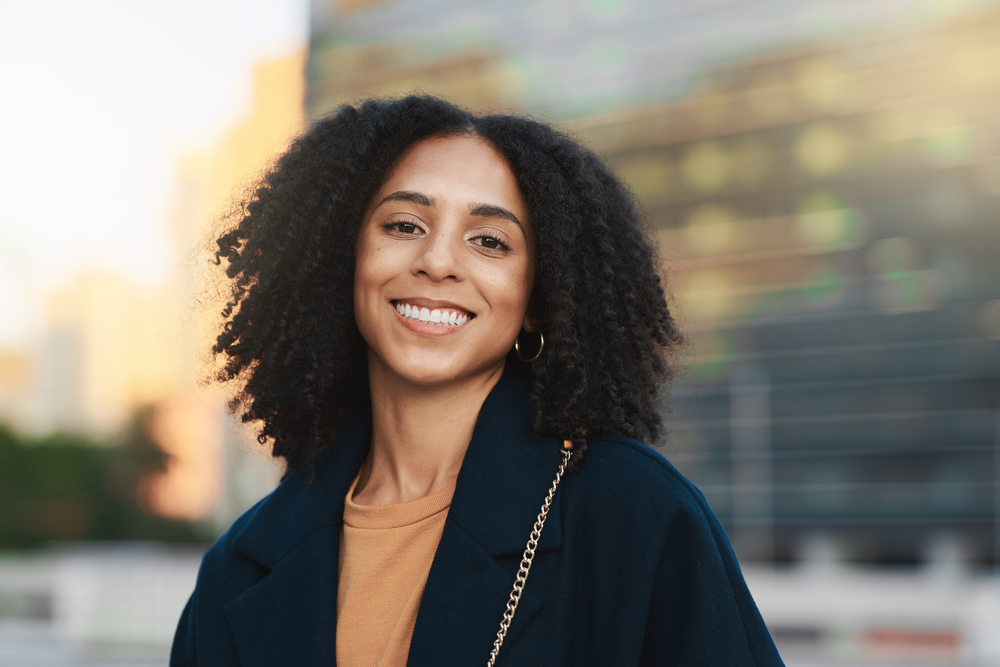 A black woman with a visible curl pattern on naturally kinky hair strands styled with organic styling creams and a leave-in conditioner.