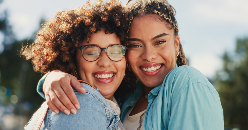 Two African American females with low porosity hair strands use essential oil products for promoting hair growth and as a natural moisturizer for an irritated scalp.