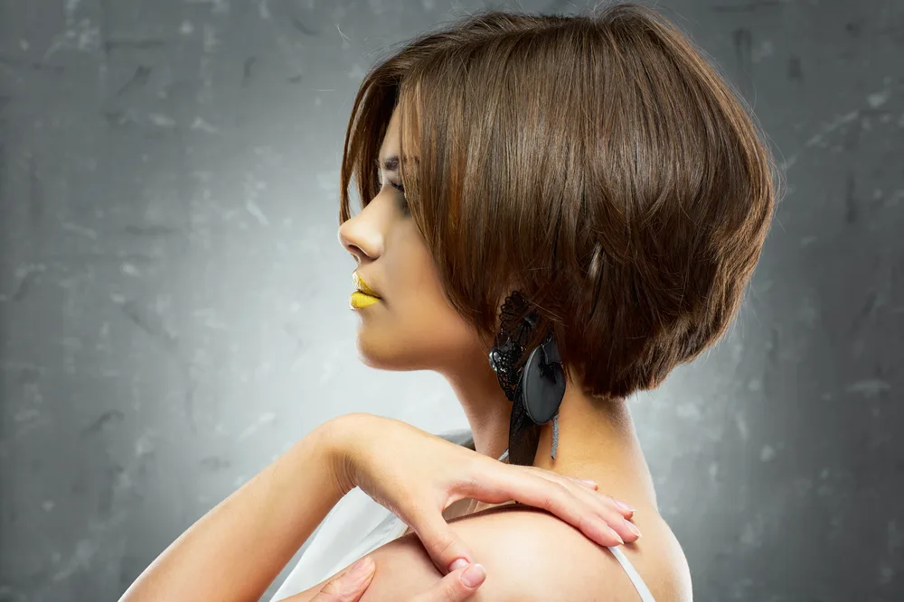 A young female wearing a beautiful bob haircut with fashionable yellow lipstick.
