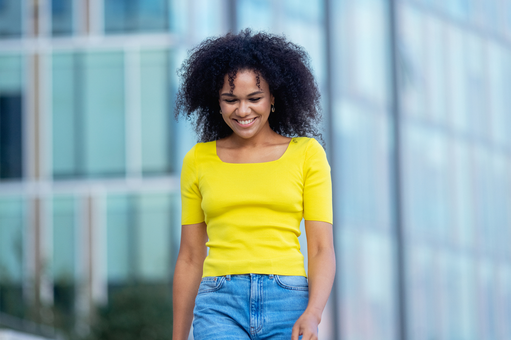 A lady with freshly washed hair used sea salt spray on her natural curls, creating effortlessly chic waves.