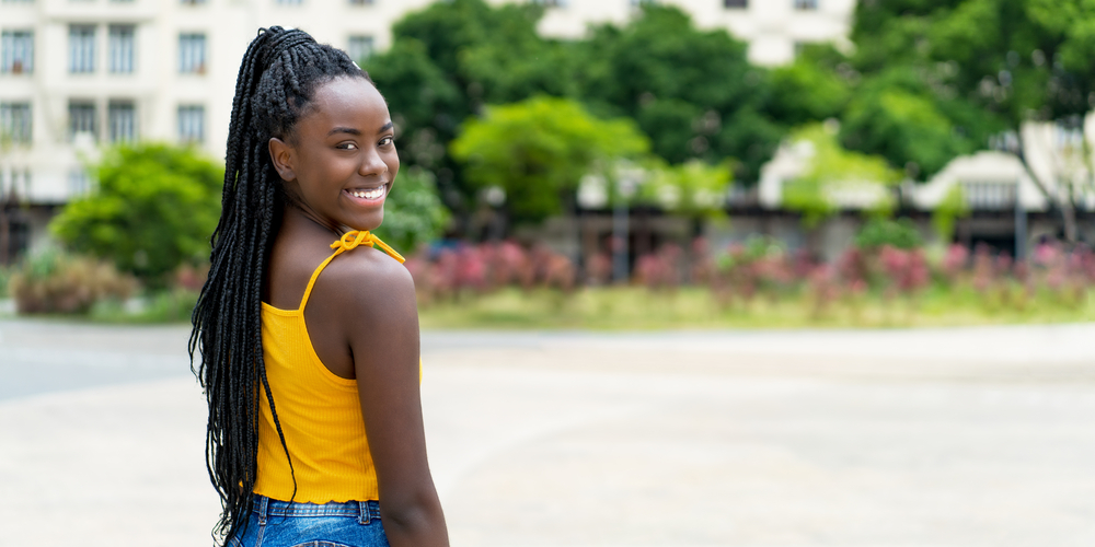 A young female standing outside wearing tailbone length dreadlocks.