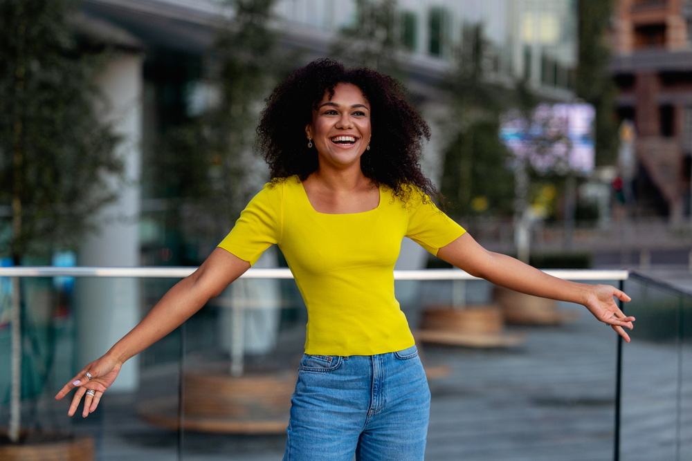 A light-skinned young black woman with naturally wavy hair that's styled with a fine tooth comb creating a messy texture.