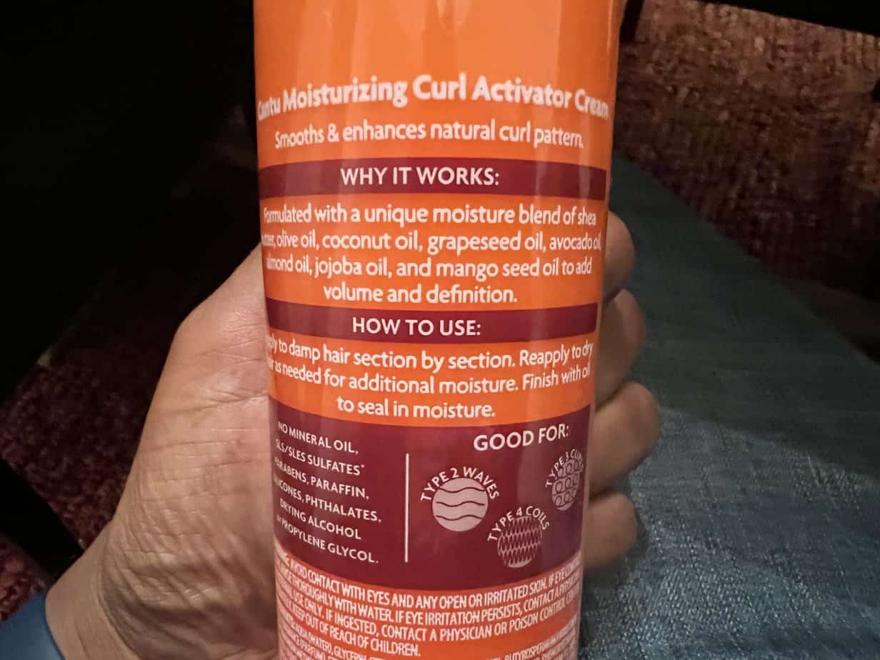 Applying Cantu Shea Moisturizing Curl Activator Cream to hair, showing its effectiveness in curl enhancement and shine.