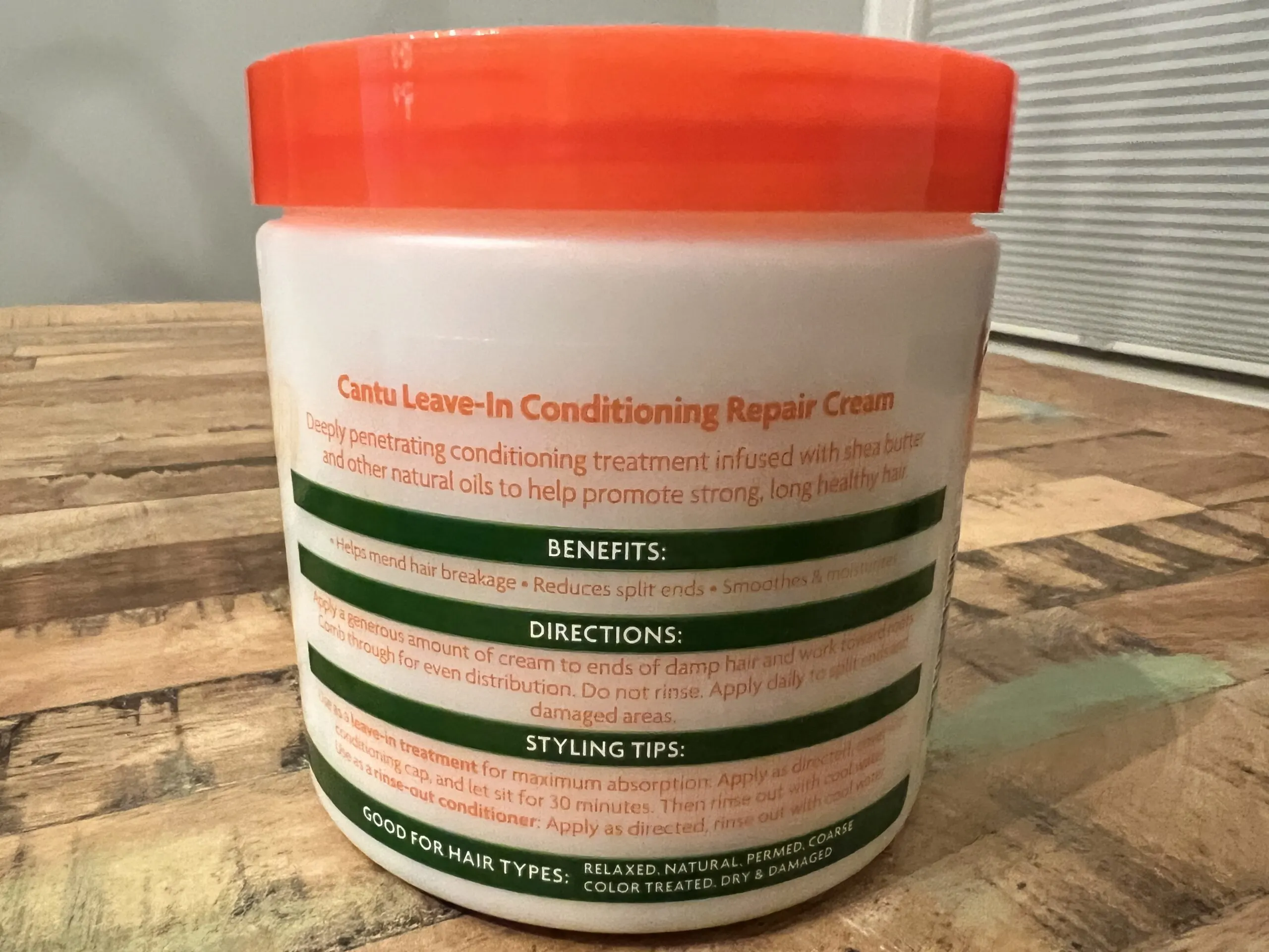 Hands applying Cantu Shea Butter Leave-In Conditioning Repair Cream, demonstrating its use for intense hair moisture and repair.