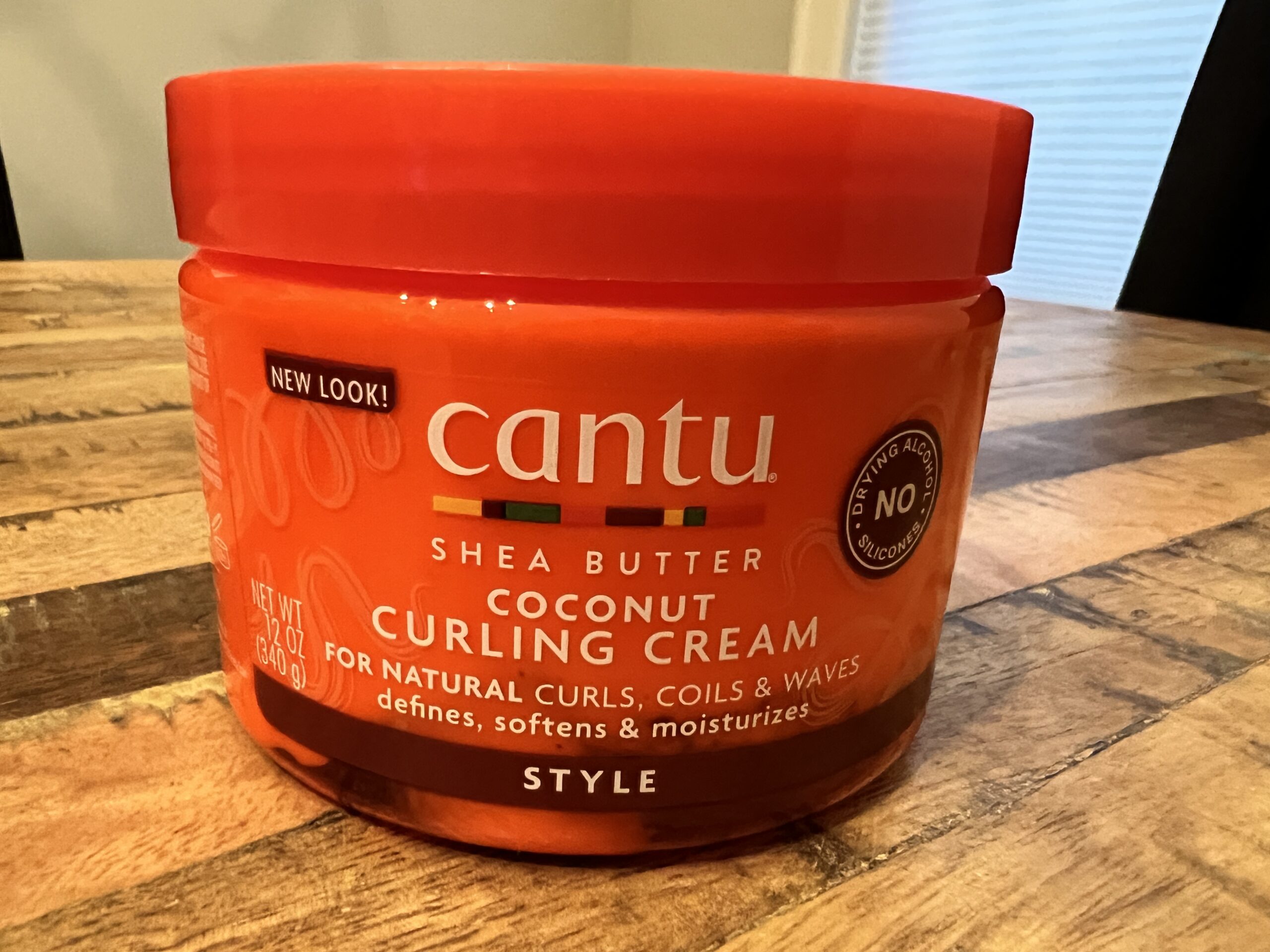 Cantu Shea Butter Coconut Curling Cream container, ideal for moisturizing natural hair textures.